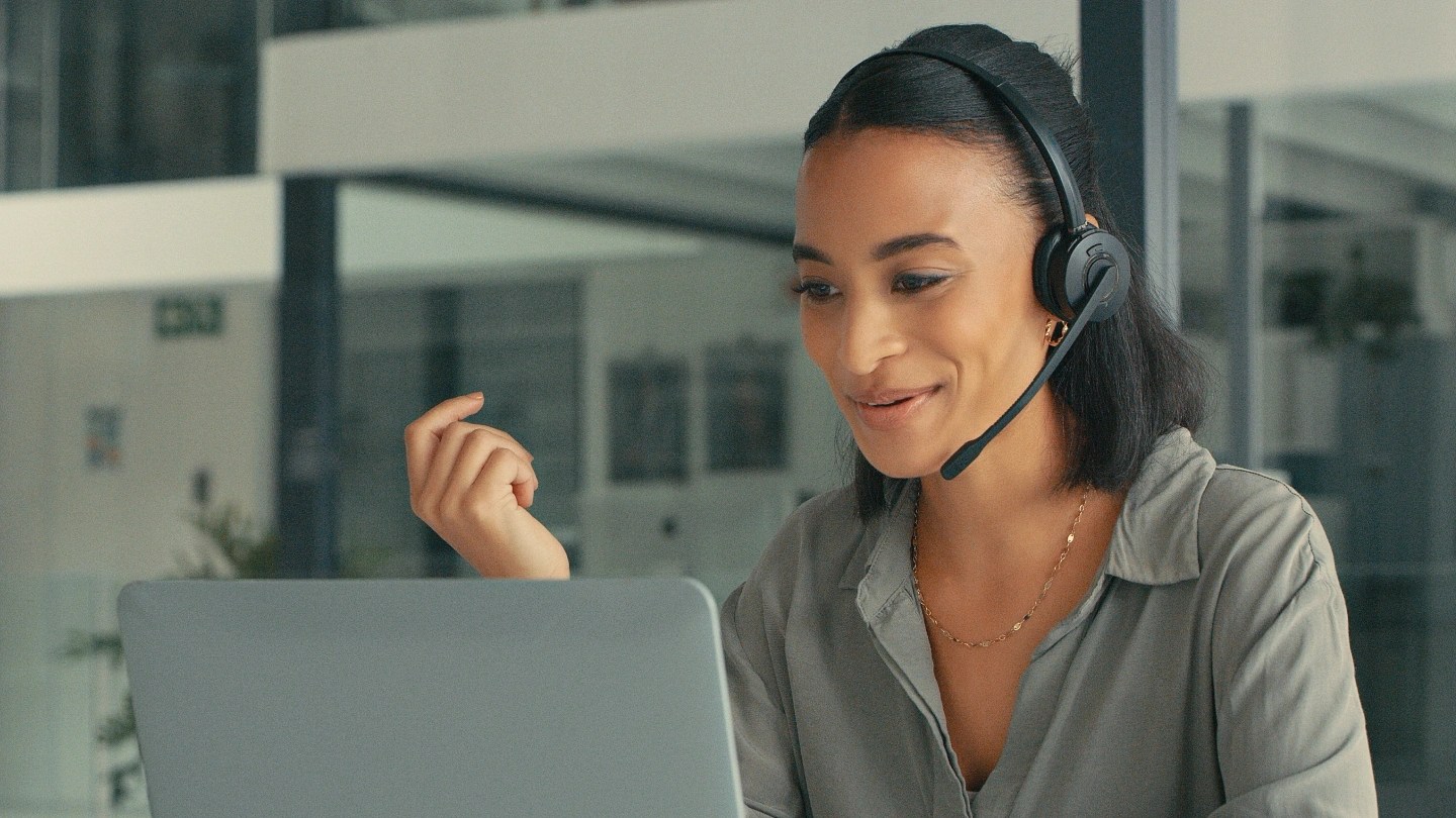 Donna al computer con cuffie e microfono