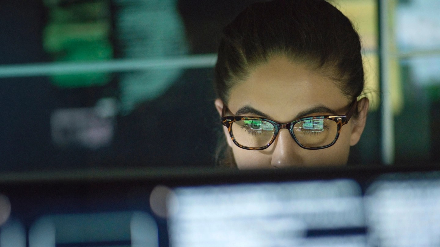 Donna con occhiali che lavora al computer in ambiente di lavoro di sera